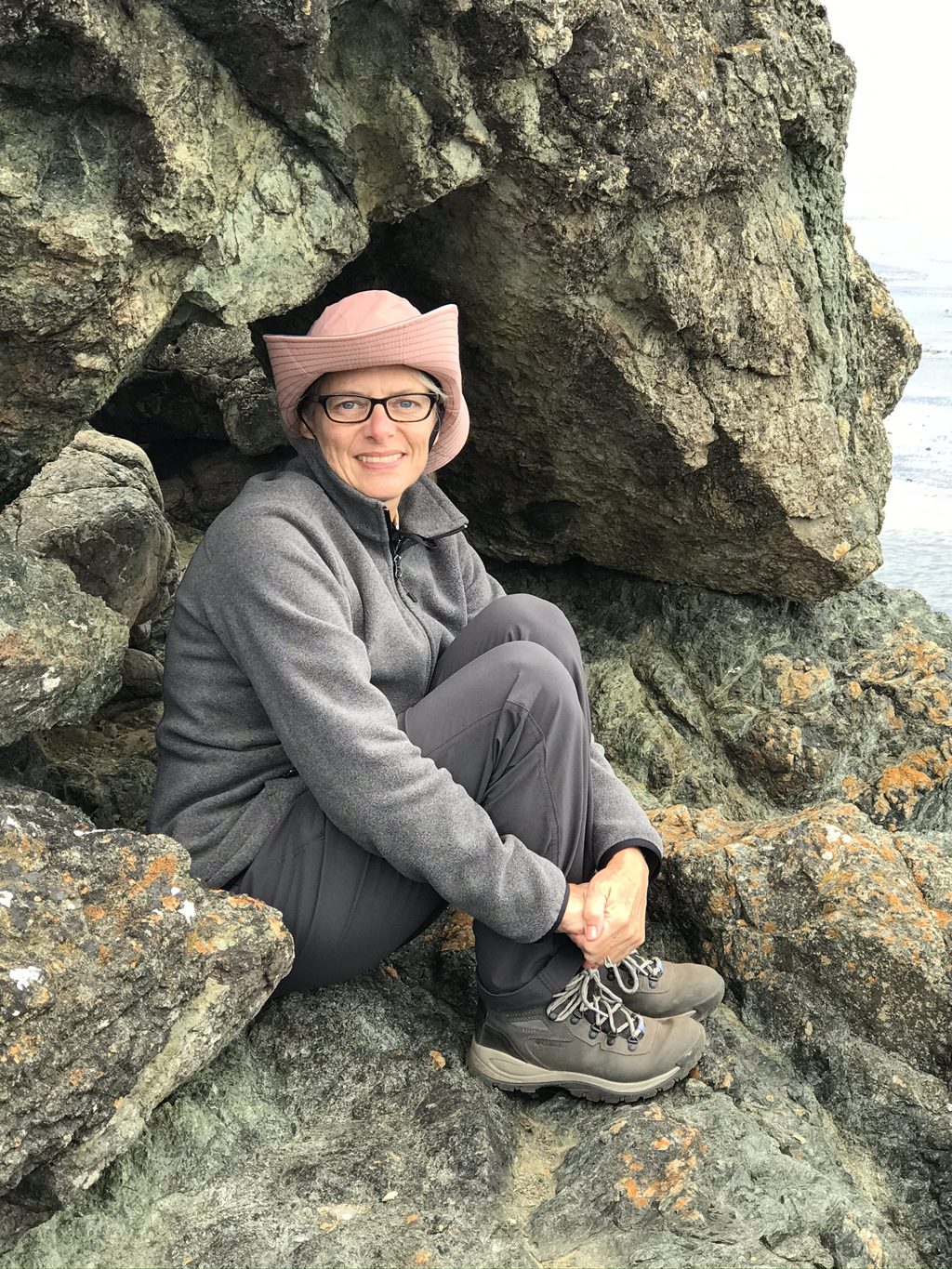 Kim Alderson among the green rocks of the point — the same stone that names Jade Cove, one cove south.