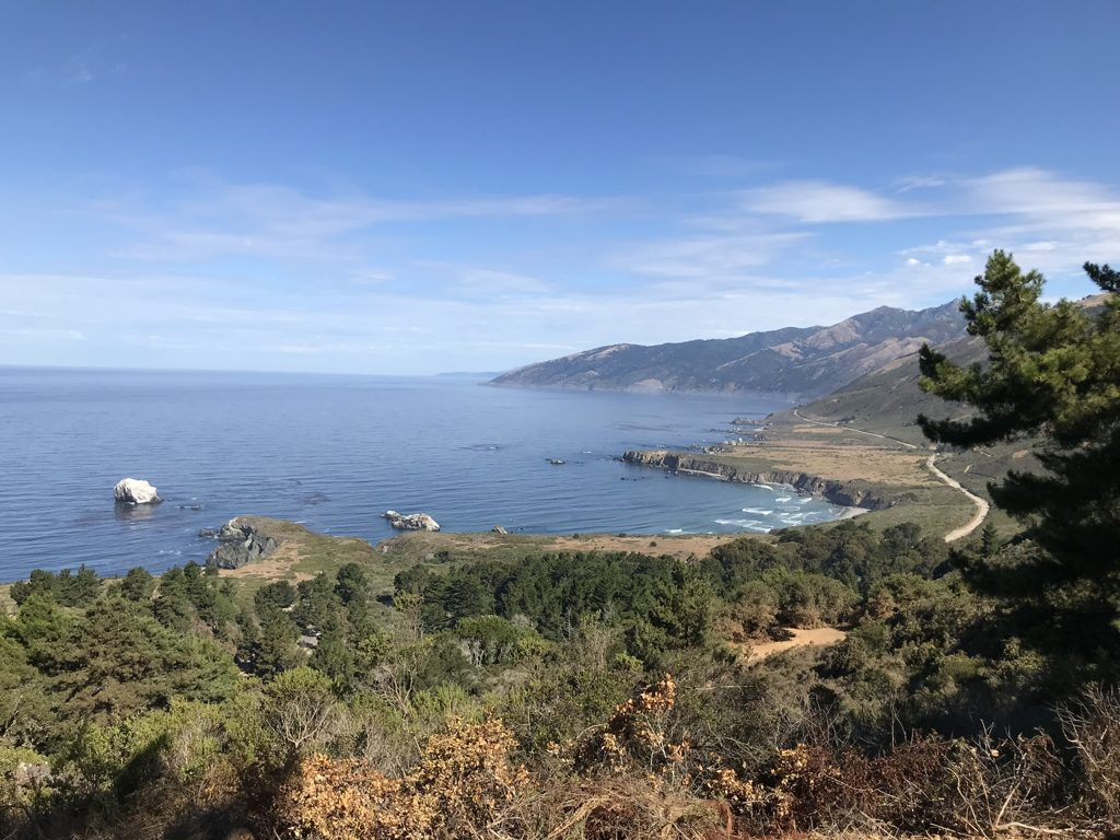 Blue-sky day on Plaskett Ridge: the whole Pacific Valley shelf — Sand Dollar's crescent, Plaskett Rock, and Highway 1 on its way south past the family's valley.